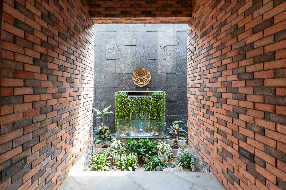 Brick-lined courtyard with a slate wall, water feature and planting